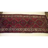 A Persian hand woven geometric runner on a red ground 290 x 116 cm approx