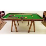 A half size slate bed snooker table top on trestle ends and accessories including cues, balls and