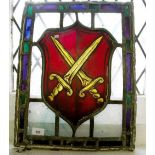 A 19th century stained glass panel with shield decoration and crossed swords, 49 x 38cm