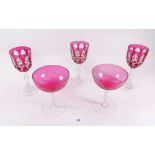 Two cranberry champagne glasses and three cranberry cut glass wine glasses