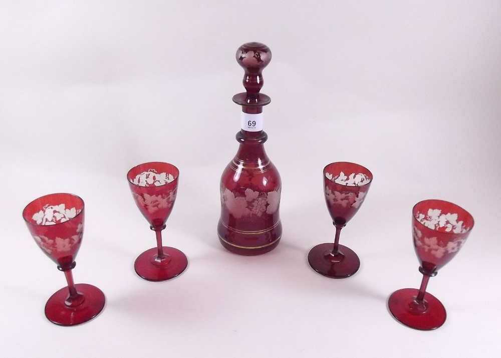 A Bohemian red flashed liquor decanter and four glasses etched vines