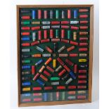 Framed and glazed cartridge display board with some 108 various paper and plastic cased collectors