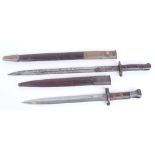 Two WW I bayonets, Enfield and Remington in metal mounted leather scabbards with frogs