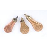 Three various copper and brass powder flasks with embossed fluted decoration