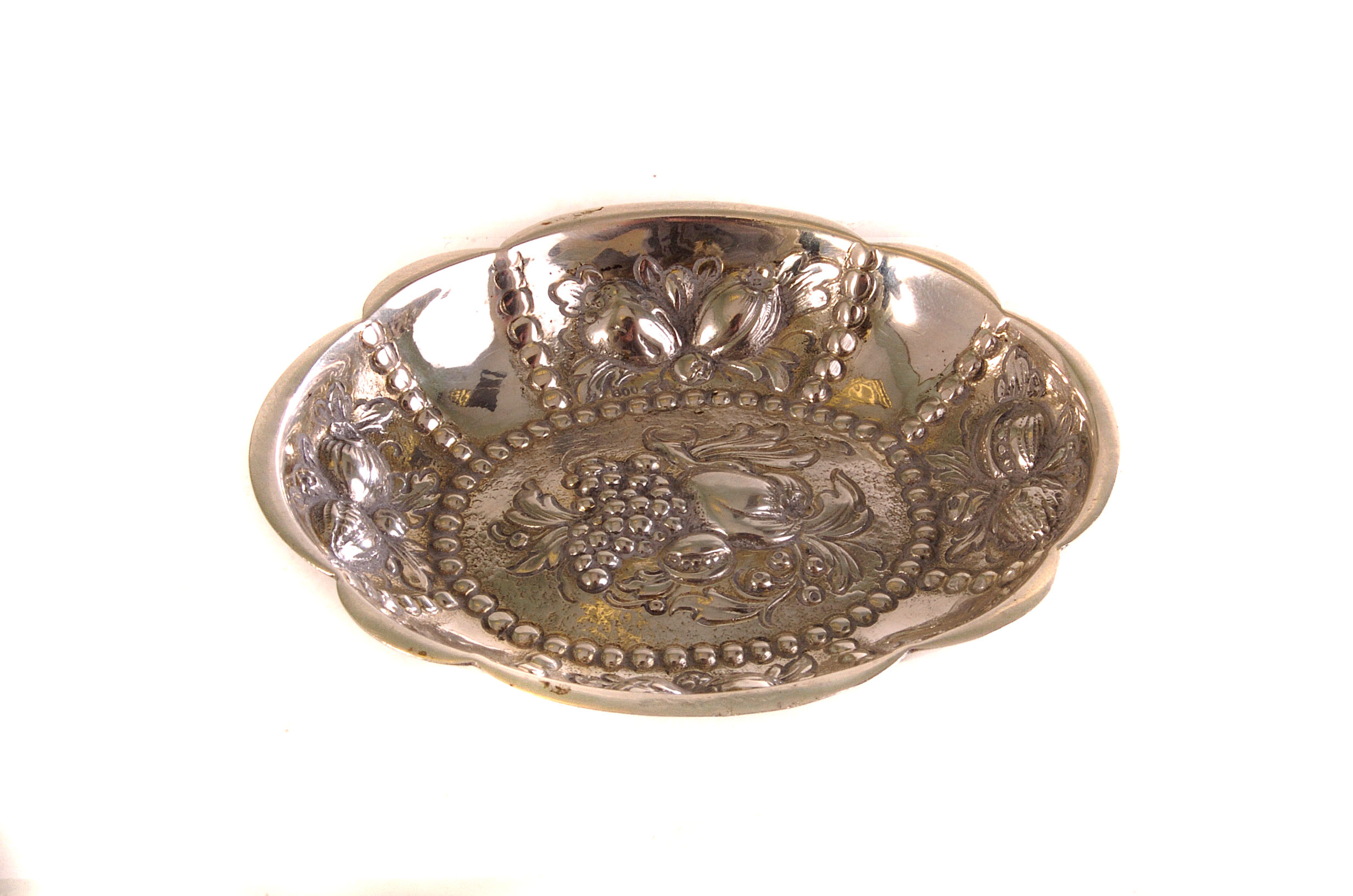An 800 marked small silver dish, having raised fruit and floral design, with beaded decoration,