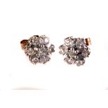 A pair of diamond cluster earrings, the diamonds set in white metal claw mounts on yellow metal base