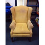 An early 20th century wing back armchair, upholstered in yellow corduroy style fabric, on shaped