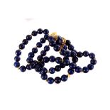 A lapis lazuli bead necklace, the 10mm beads separated by small yellow metal beads, with large