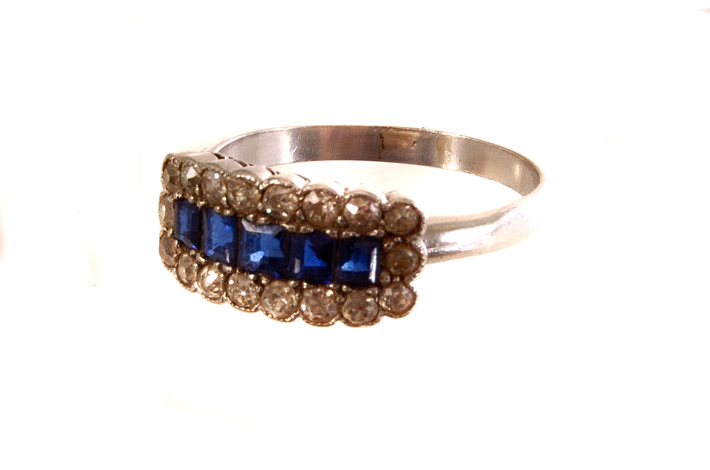 A white metal sapphire and diamond ring, the five square cut sapphires surrounded by round cut