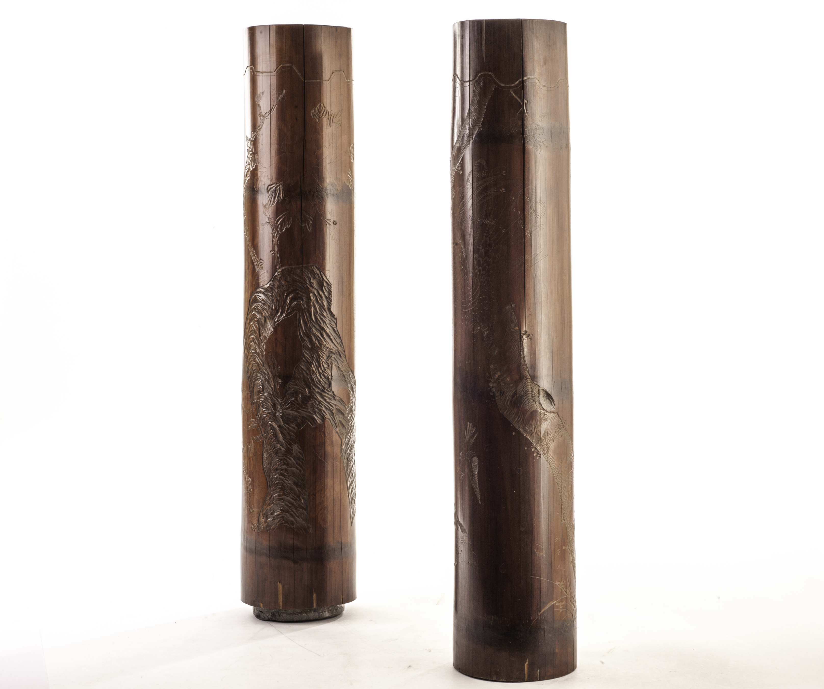 A pair of Chinese bamboo stick stands, the long cylinders with lead weighted bases having carved