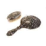 A silver backed Victorian hand mirror and brush, the mirror having cherub and floral design, the