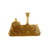 A cut glass dressing table set, in amber, comprising lidded pots, a tray and a pair of candles (