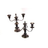Two pairs of silver plated candelabras, each of similar design with stoppers for central candle