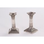 A pair of late Victorian silver filled candlesticks by Edward Hutton, having square bases supporting