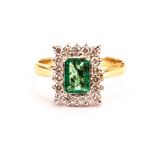 A Middle Eastern rectagular gem set cluster ring, having an emerald style green stone surrounded