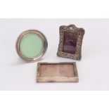 Three small silver photograph frames, one with embossed frame, one circular and one rectangular (3)