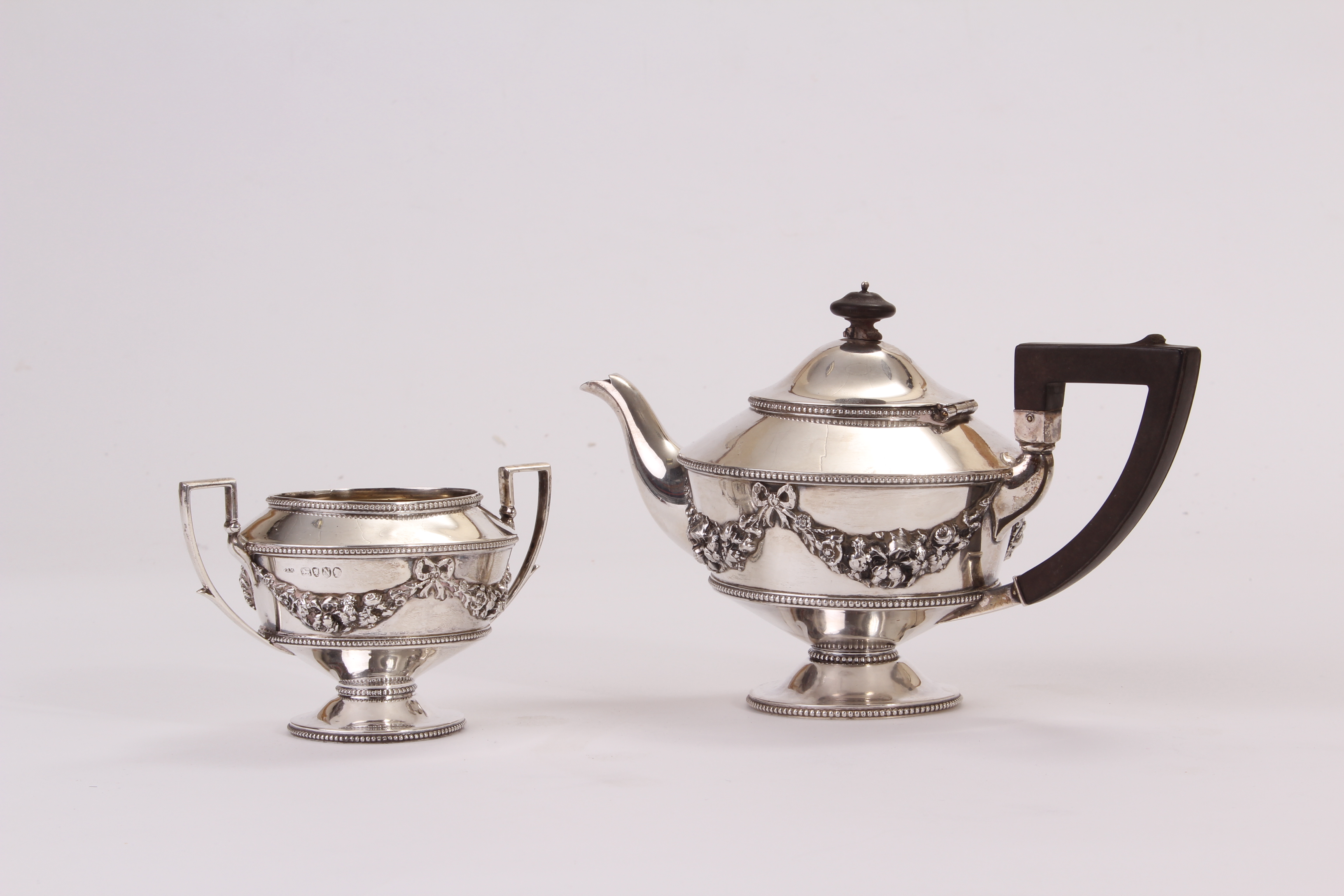 A Victorian silver tea pot and sucrier, decorated with swags and bows, on a footed base,