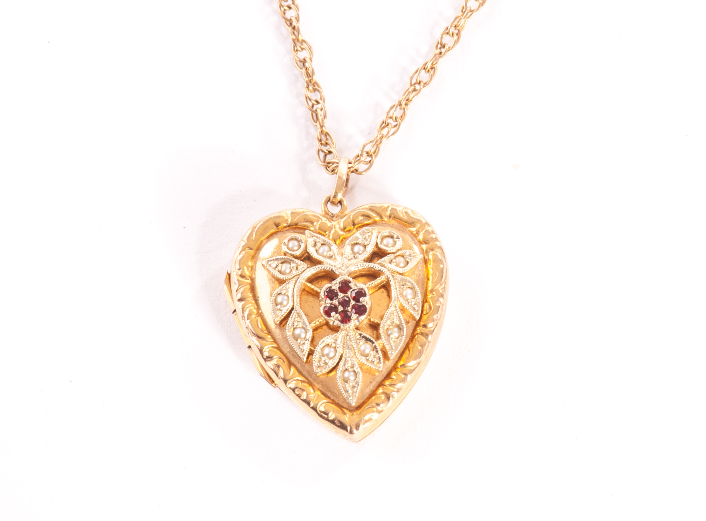 A pretty 9ct gold heart shaped locket, the front with floral design set with seed pearls and
