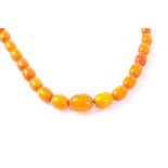 An amber bead necklace, the Art Deco period toffee graduated beads on brown cotton necklace,