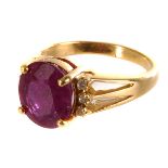 An 18ct gold ruby and diamond dress ring, the large oval cut ruby in four claw setting flanked by