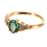 An 18K marked emerald and diamond dress ring, the oval cut emerald flanked by three round cut