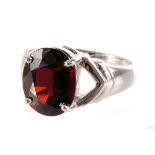 A 9ct white gold garnet dress ring, the large oval cut stone in four claw setting, having pierced