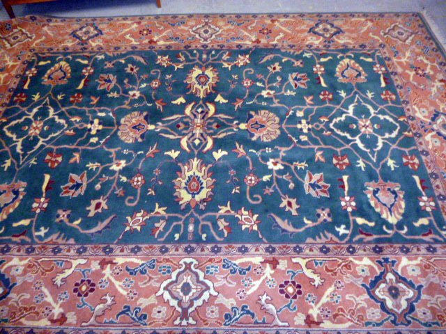 A large green ground machine knotted carpet, having central green ground florally decorated panel,