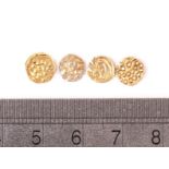 A group of four ancient gold coins, one having elephant design, two with stylised T or arrow, the