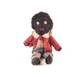 A British 1920s Golliwog, of black cloth, red embroidered nose, mouth and shoe laces, linen button