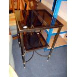 A smoky glass and brass side table, having square glass top insert and similar lower shelf