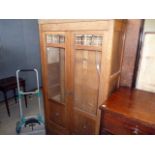 A glazed display cabinet, the two glazed doors with bevelled glass tiled design to top, opens to