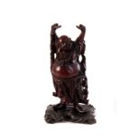 A carved wooden figure of a Buddha, in traditional ceremonial dress, looking to be happy, possible
