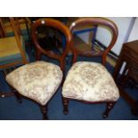 A pair of mahogany balloon back chairs, upholstered in floral swag material, on turned front legs