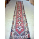 A red ground Turkish hall runner, having multiple cross medallions surrounded by geometric multi-