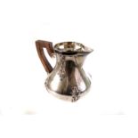 A French silver milk jug, having wooden handle and raised floral swag design, with partial impress