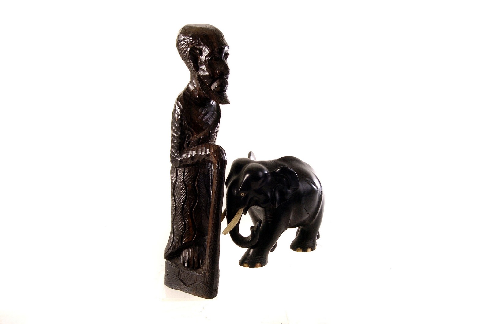 An African carved figure of an elderly gentleman, together with a selection of ebony elephant