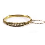 A Victorian 15ct gold diamond and seed pearl bangle, one half with bead borders and a row of