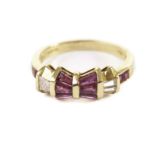 A modern 18ct gold ruby and diamond dress ring, the bow style tablet set with tapered red and