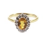 A fire opal and diamond cluster ring, the oval orange stone surrounded by brilliant cuts in platinum