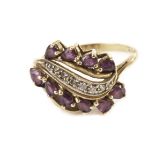 A 14ct gold and gem set dress ring, having a spray of red cut stones flanking a row of small