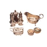 A George V silver sauce boat, together with a pair of silver pepperettes / sifters, a silver mounted