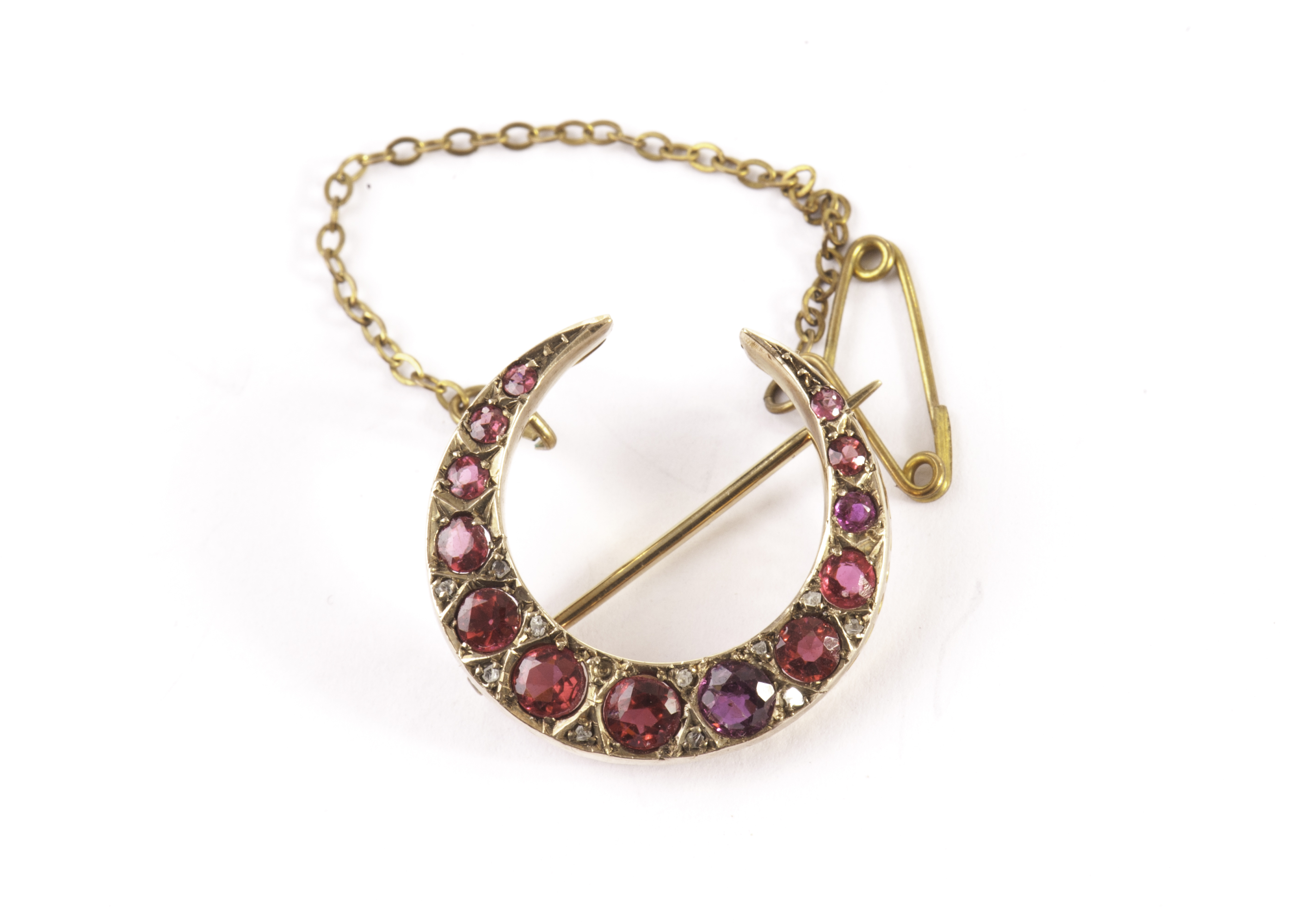 A pretty ruby and diamond brooch, in the form of a crescent set with round cut red stones and