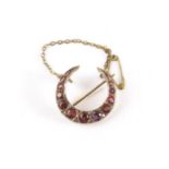 A pretty ruby and diamond brooch, in the form of a crescent set with round cut red stones and