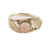 A French 15ct gold and coral ring, having two leaves and cabochon pink coral bead to tablet,