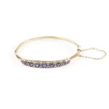 An Edwardian 9ct gold and gem set bangles, having a row of graduating sapphires interset with