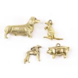 A yellow metal canine brooch and three 9ct gold charms, the dog brooch in the form of a dachshund