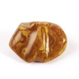 An Art Deco period amber pebble brooch, the opaque toffee colour polished piece of amber with