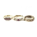 A group of three gem set dress rings, comprising an eternity ring, a three row cluster ring, and