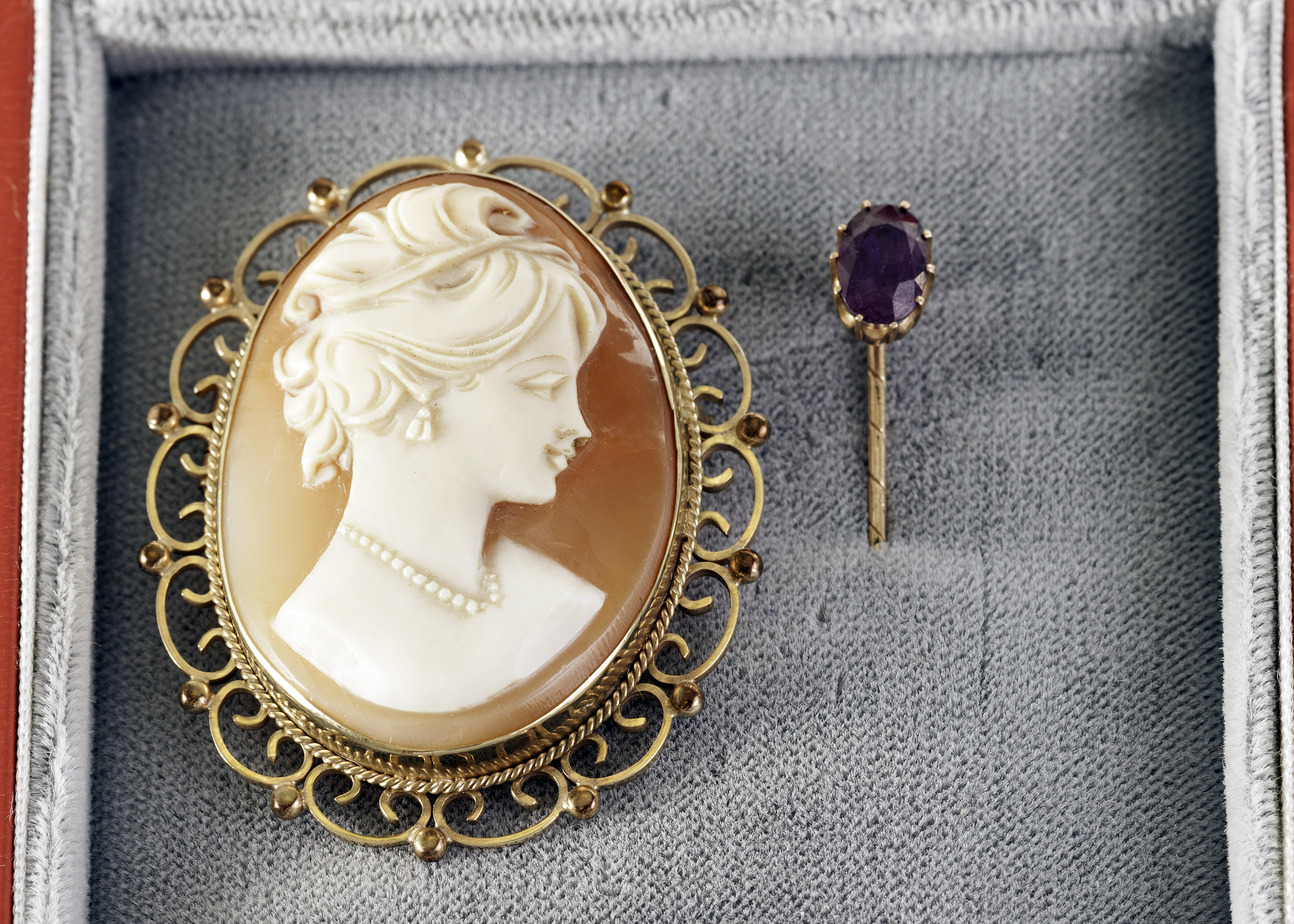 An antique gold and ruby stick pin, together with a yellow metal shell cameo brooch (2)