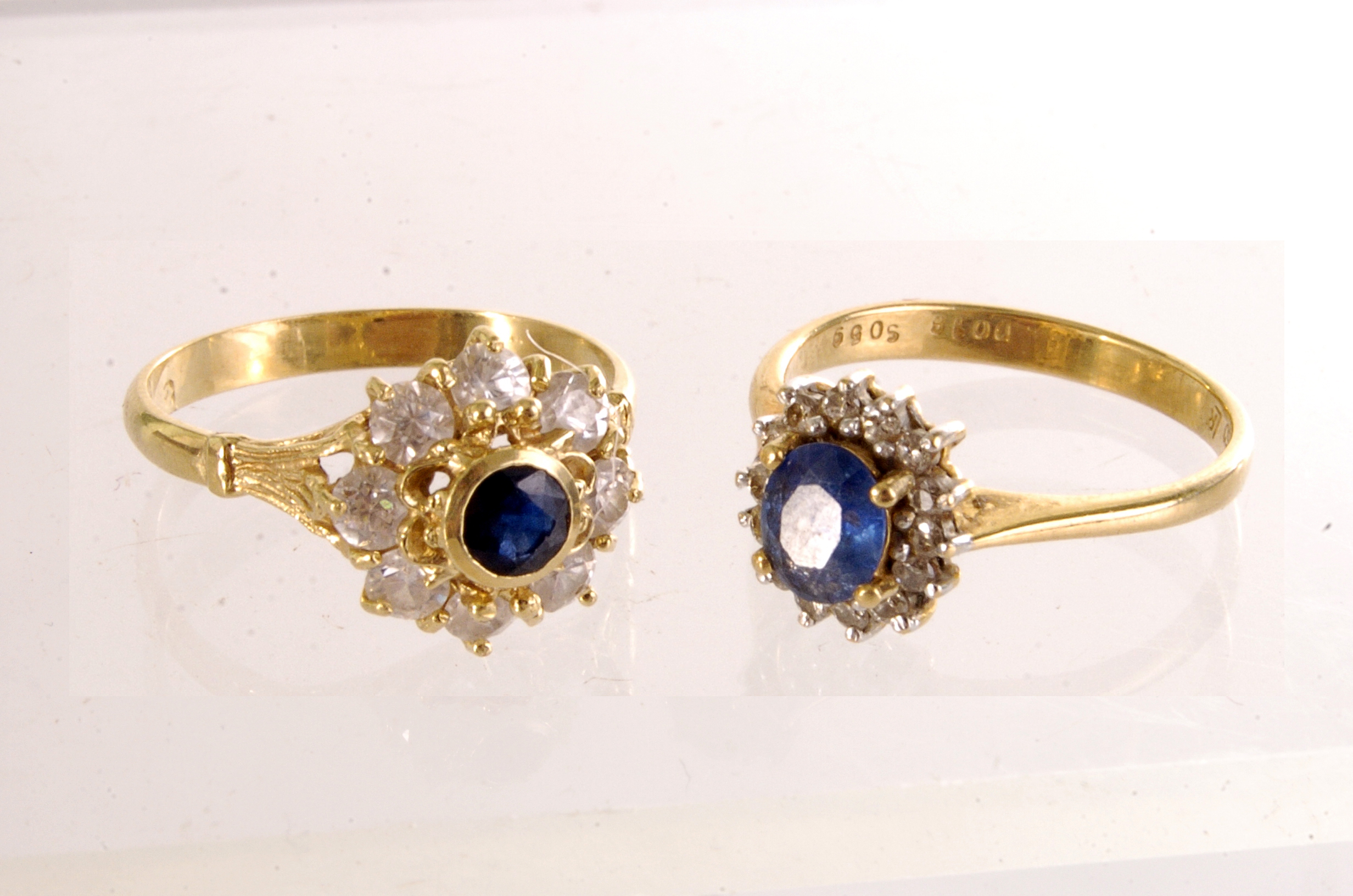 Two yellow metal and gem set cluster rings, both marked 750, with a central blue stone surrounded by